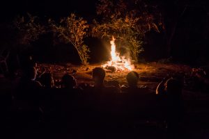 Photo of participants reflecting near an inviting bonfire.