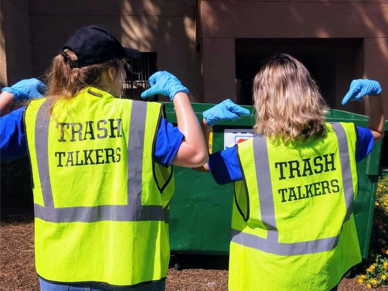two people wearing yellow vests that read trash talkers