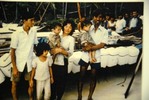 Ông Trương Quang Tố (bìa phải) và vợ con bên chiếc thuyền nan, vượt biên năm 1987, đến Thái Lan. (Hình chụp lại: Linh Nguyễn/Người Việt)